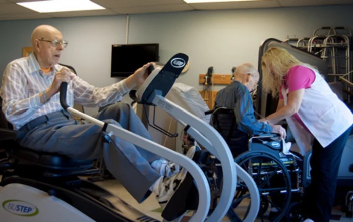 Elderly individuals engaging in physical therapy exercises using specialized equipment in a healthcare facility.