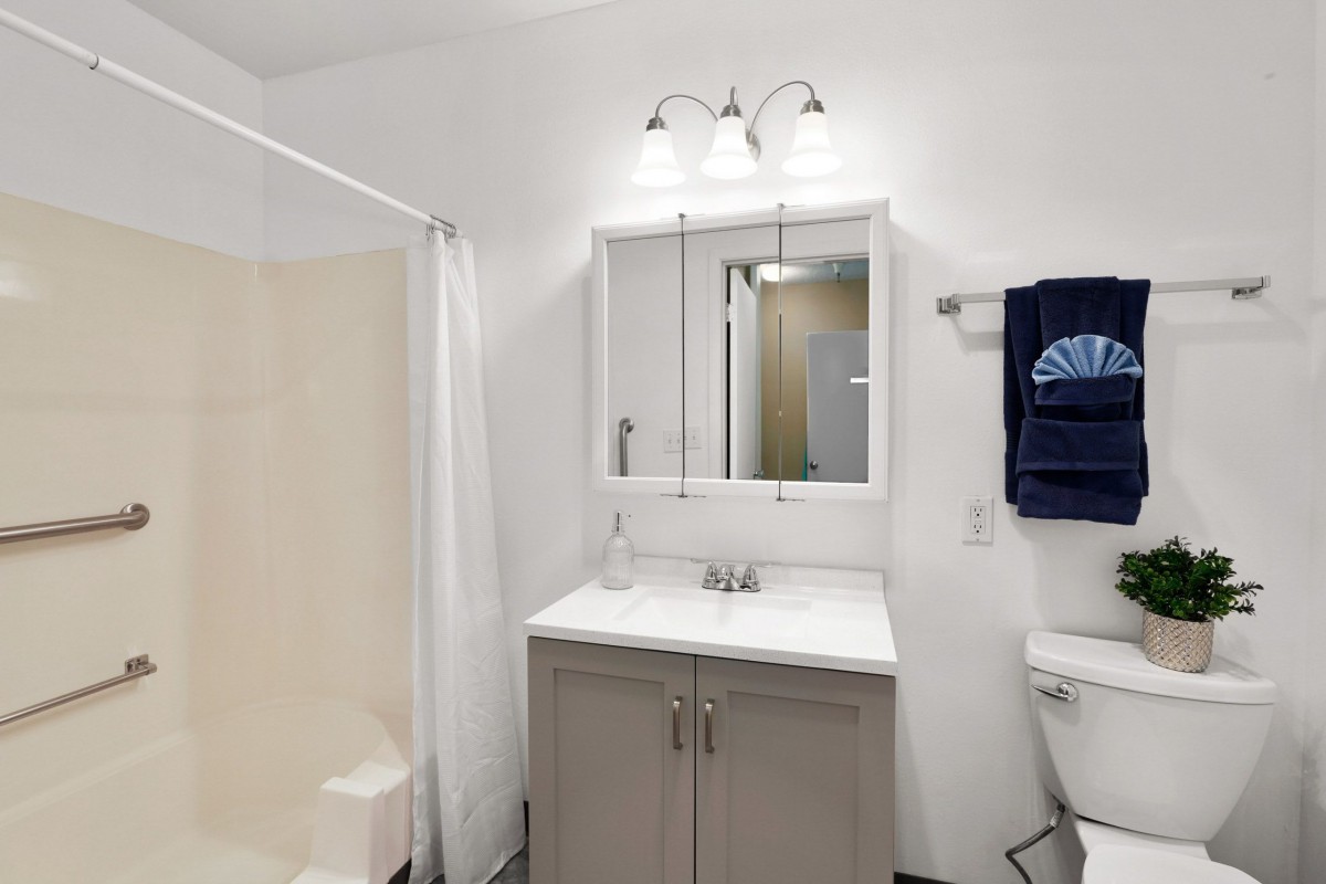 A clean and modern bathroom with a mirror, sink, and shower.