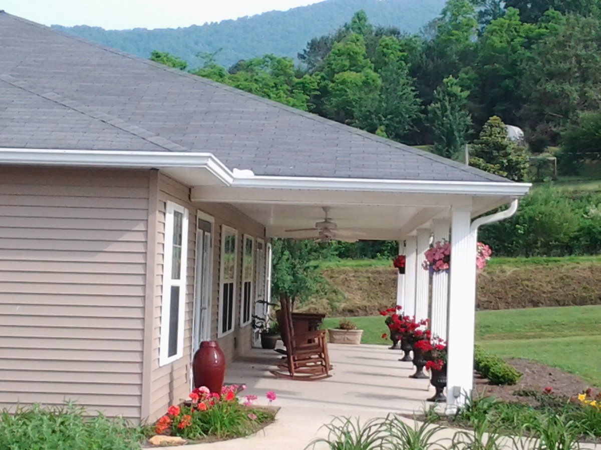 A charming house with a porch, set against a scenic mountain backdrop.