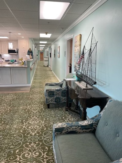 A hallway with a comfortable waiting area featuring chairs, a model ship, and decorative elements.