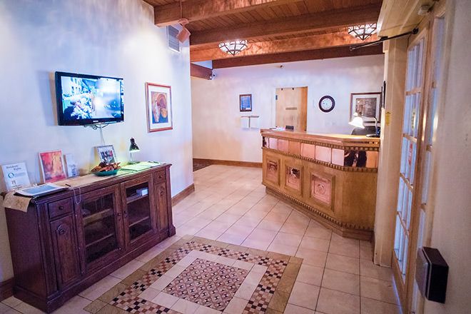 A cozy lobby area featuring a wooden reception desk, wall-mounted TV, and decorative artwork.
