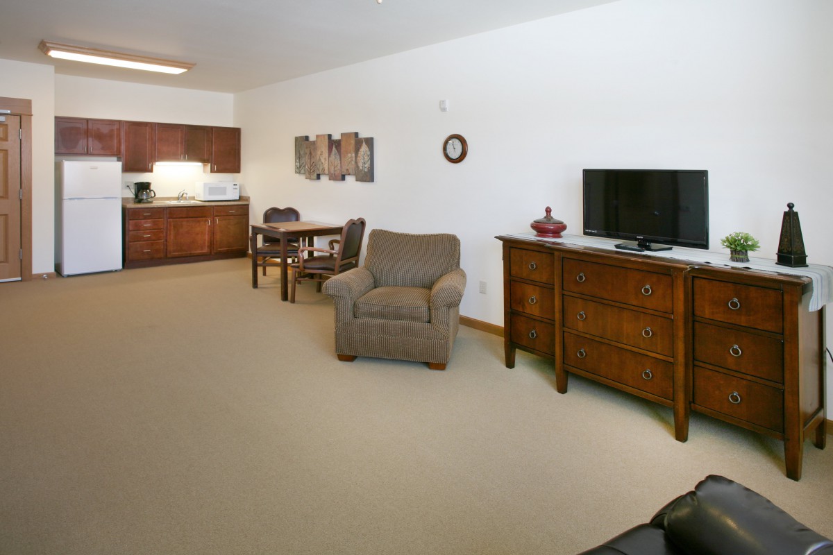 A cozy living space with a television, comfortable armchair, and dining area near the kitchen.