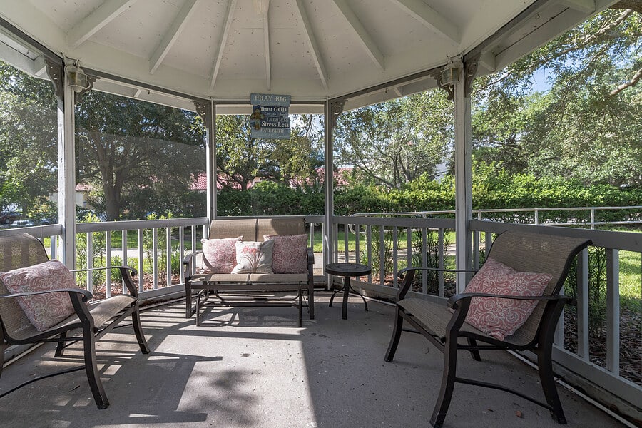 A cozy gazebo with comfortable patio furniture, perfect for relaxing in a garden setting.