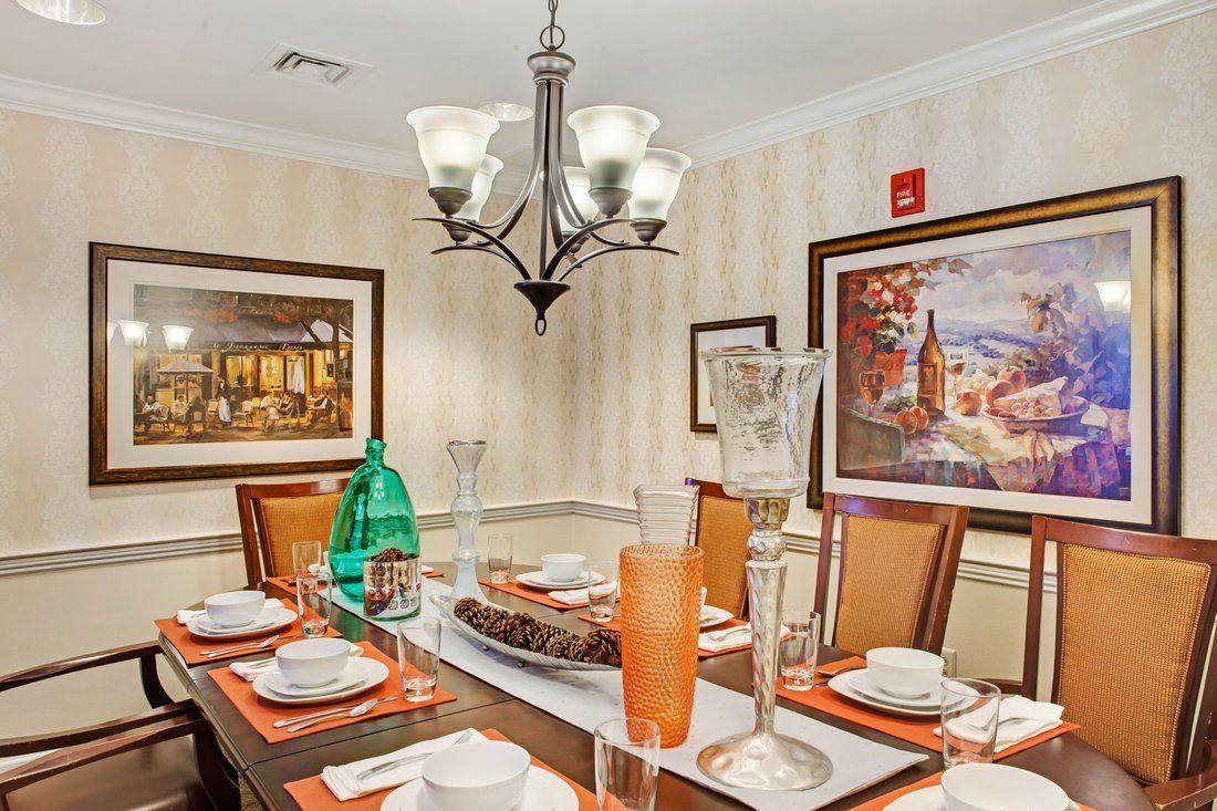 An elegantly set dining table with a chandelier overhead and framed artwork on the walls.