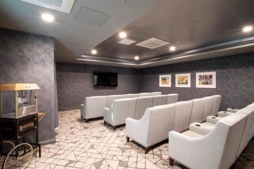 A modern lounge area with rows of comfortable seating, a television, and wall art under soft lighting.