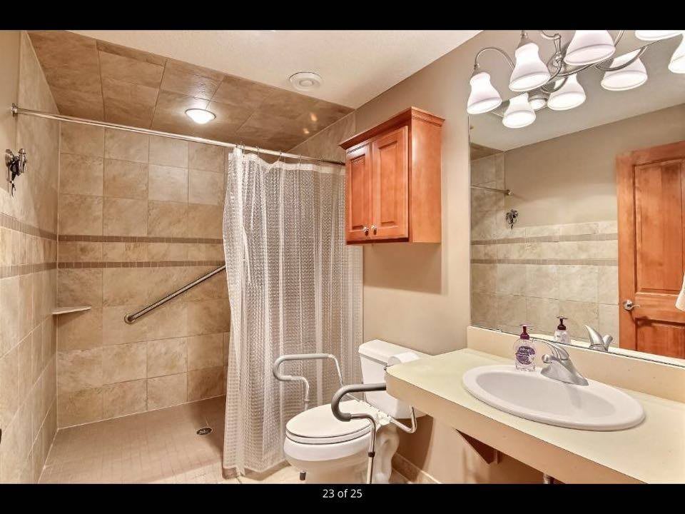 A modern bathroom with a tiled shower area, a sink, and a toilet.