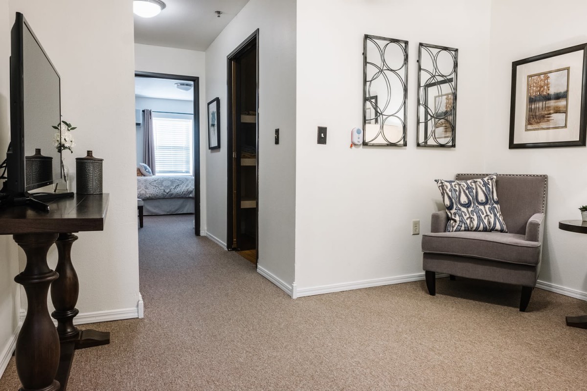 A modern living area with neutral tones features a hallway leading to a bedroom.