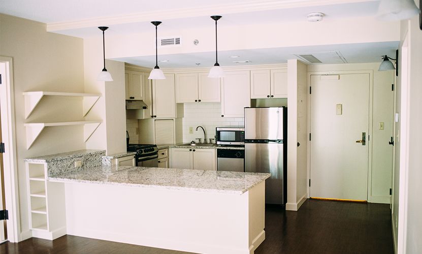 Modern kitchen interior with stainless steel appliances and pendant lighting.