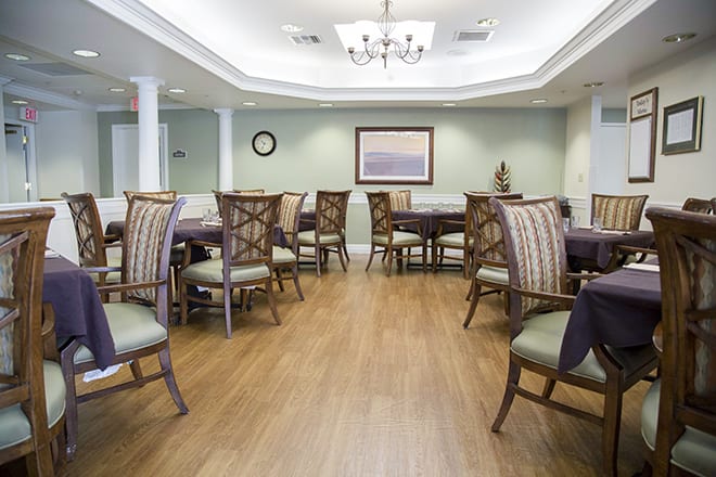 A well-arranged dining room with elegant chairs and tables, wooden flooring, and a chandelier.