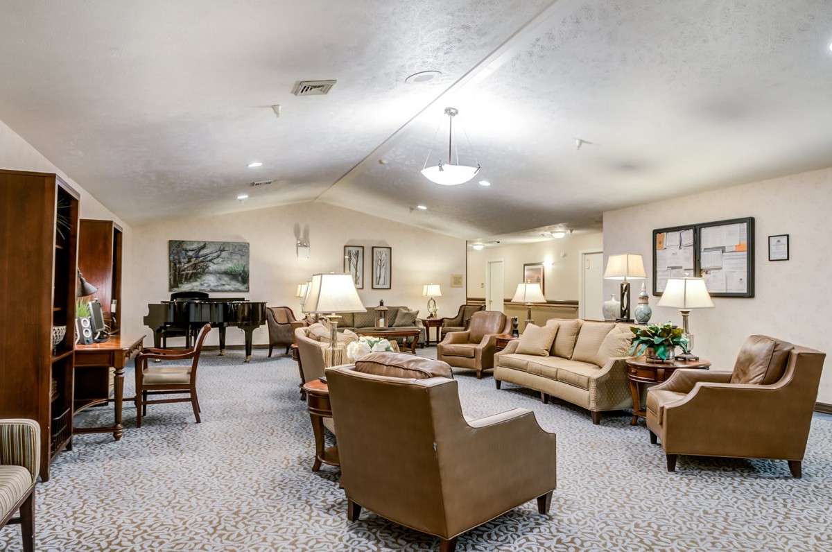 A spacious and elegantly furnished living room with sofas, armchairs, and a piano.