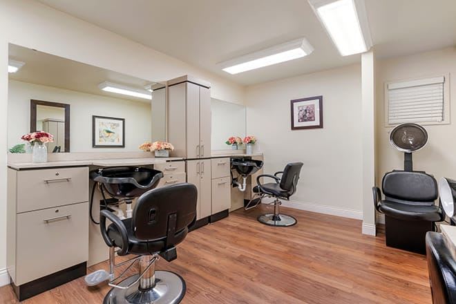 A modern hair salon interior with styling chairs and mirrors, featuring wood flooring and bright lighting.
