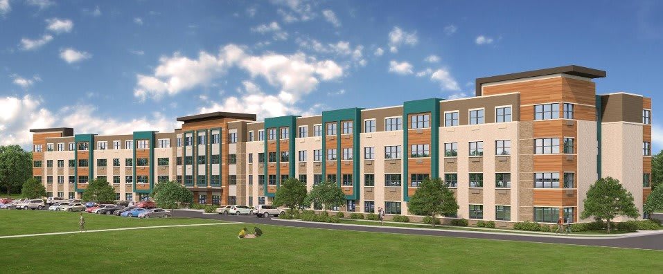 A modern apartment building with a green lawn and a partly cloudy sky.