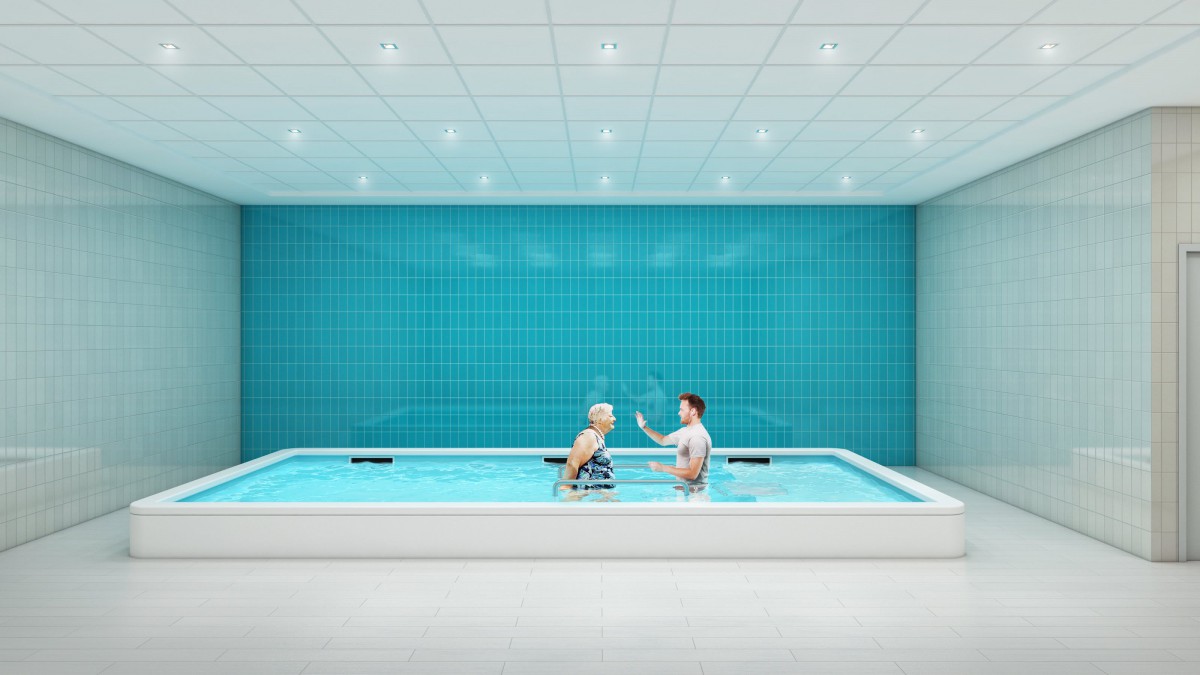 Two people engaging in aquatic therapy in an indoor pool with blue tiled walls.