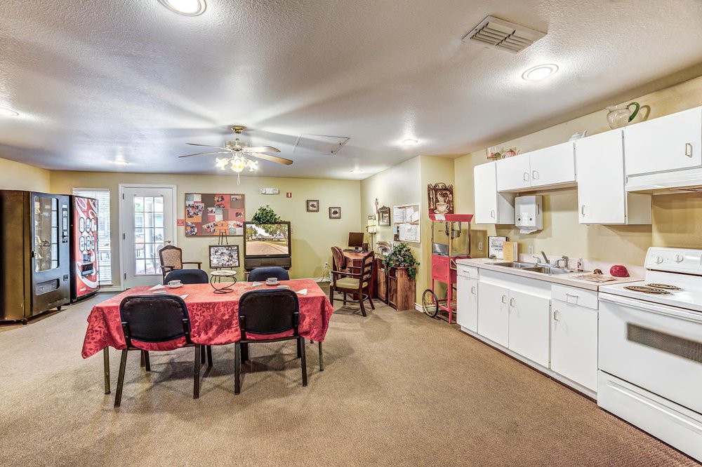 A cozy indoor kitchen and dining area with a table set for dining, surrounded by chairs and decorated with wall art and potted plants.