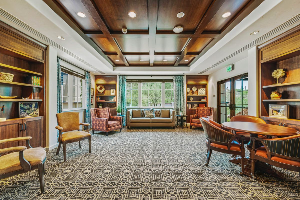 A cozy and elegant living room with comfortable seating, a patterned carpet, and large windows.