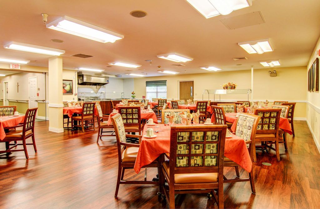 A well-lit dining area with neatly arranged tables and chairs, featuring a warm wooden floor.