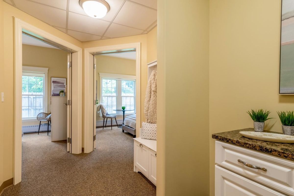A cozy hallway leading to a bright bedroom with large windows.