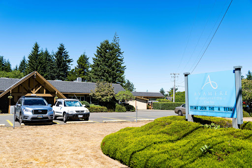 A serene neighborhood scene featuring parked vehicles, well-manicured greenery, and clear blue skies.