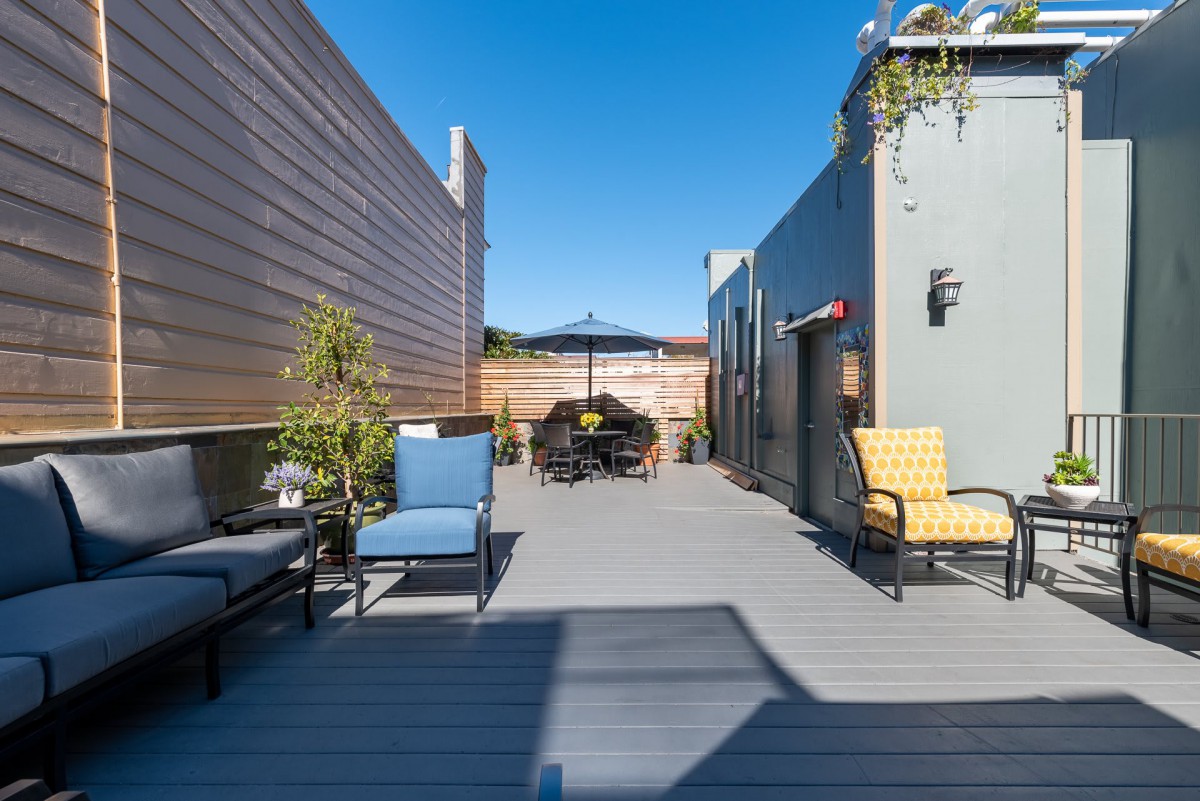 A modern rooftop patio with comfortable seating and clear blue skies.