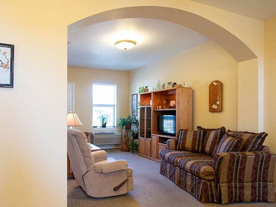 A cozy living room with a sofa, armchair, and television.