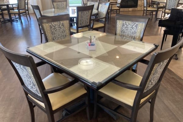 A dining area with a square glass-top table surrounded by four chairs.