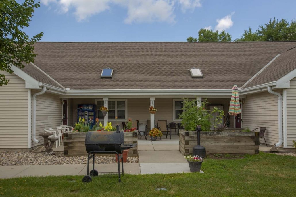 A backyard patio area featuring outdoor furniture, a barbecue grill, and skylights on the roof.