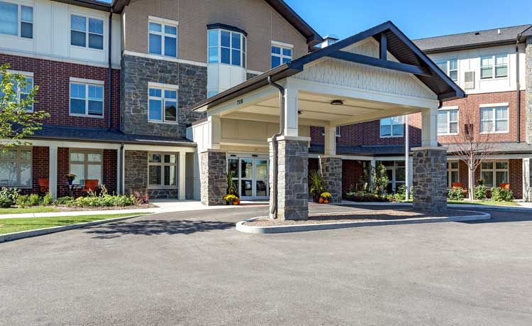 The image shows the entrance of a modern commercial building with stone accents and large windows.