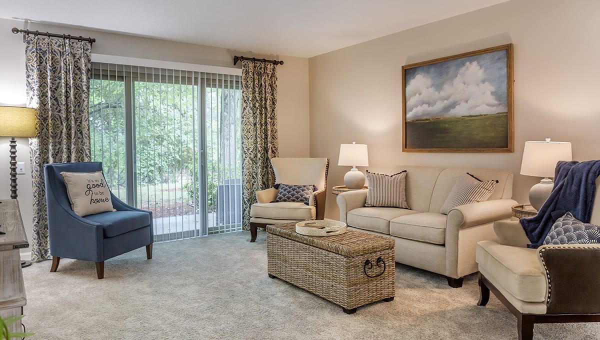 A cozy living room featuring a sofa, armchair, and coffee table with a lamp and artwork on the wall.