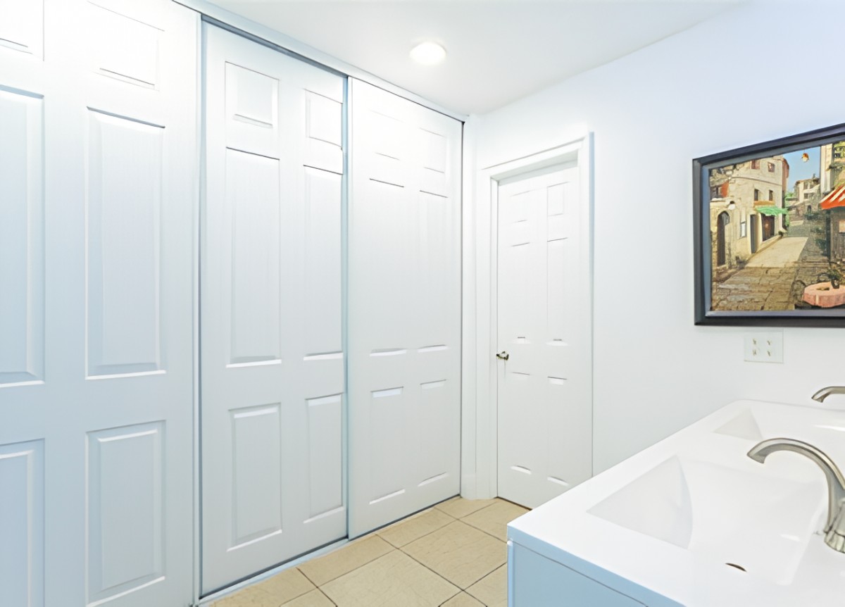 A modern minimalist hallway featuring white sliding closet doors and a tiled floor.
