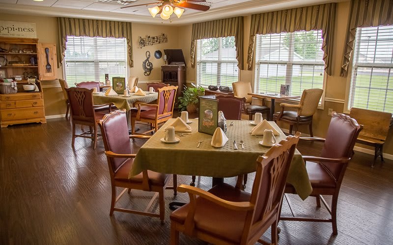 A cozy dining area with neatly arranged tables and chairs, illuminated by natural light.