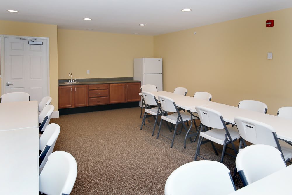 A small conference room with folding chairs and tables, featuring beige walls and a carpeted floor.