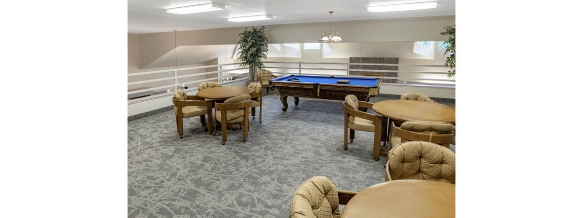 A recreational game room featuring a pool table and several tables with chairs.
