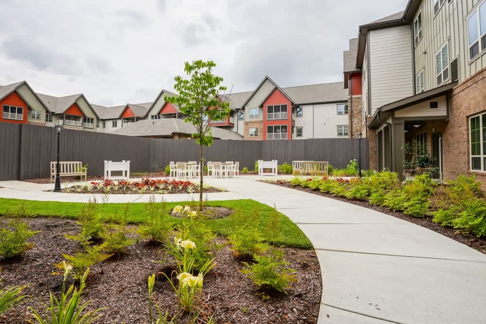 A landscaped garden with a winding pathway and outdoor seating area in an apartment complex.