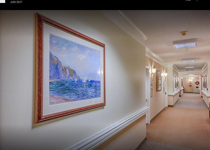 A well-lit hallway featuring framed artwork on the wall.