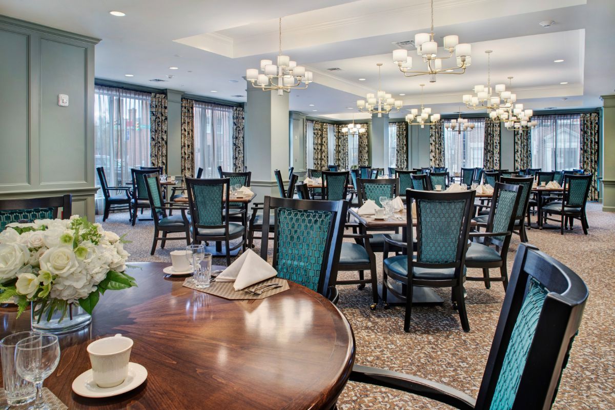 An elegant dining room set with tables and chairs, featuring sophisticated lighting and decor.