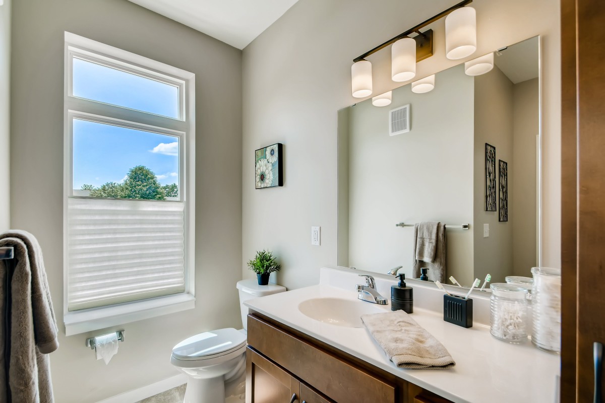 A modern bathroom with a sleek design, featuring a sink, mirror, and natural light coming through the window.