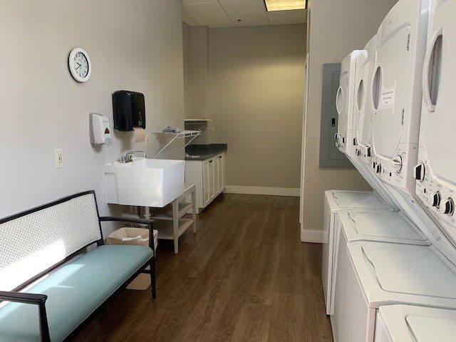 A clean and organized laundry room featuring washers, dryers, and a folding table.
