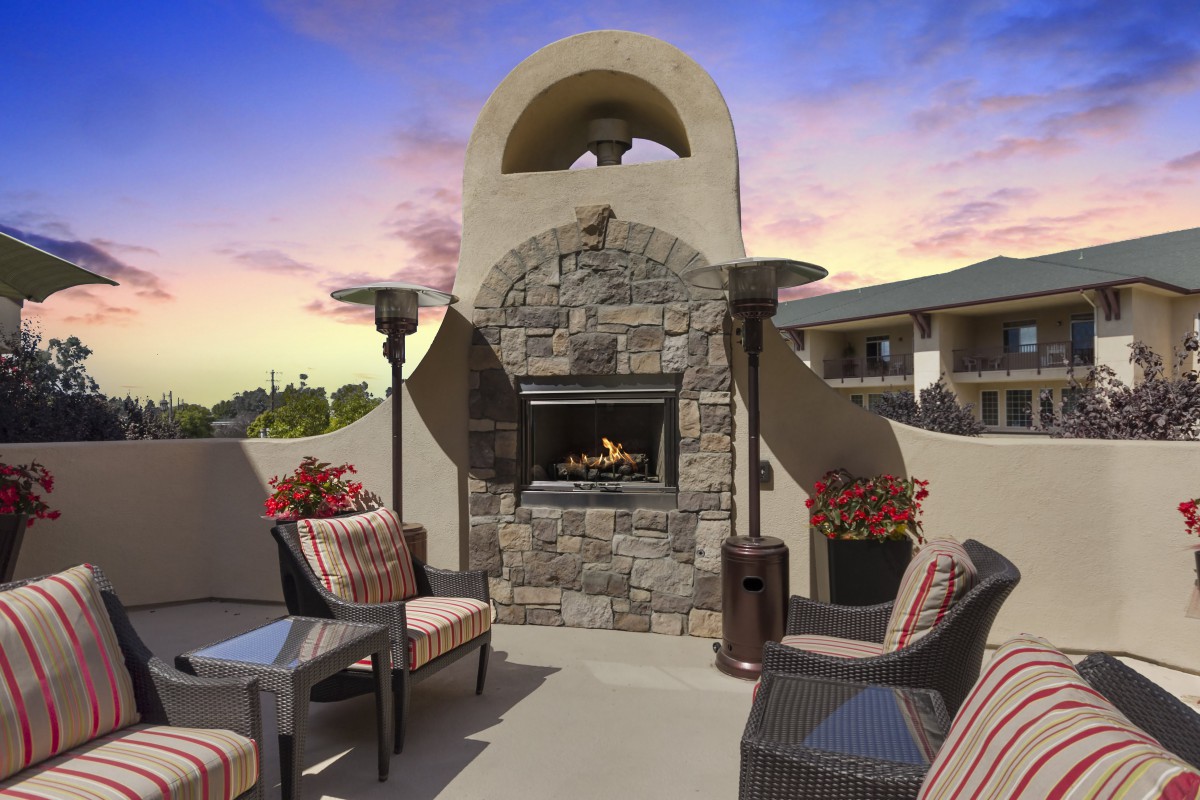 A cozy outdoor patio with a stone fireplace and comfortable seating arrangements during sunset.