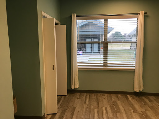 A bright and airy interior space with a window, door, and wooden flooring.