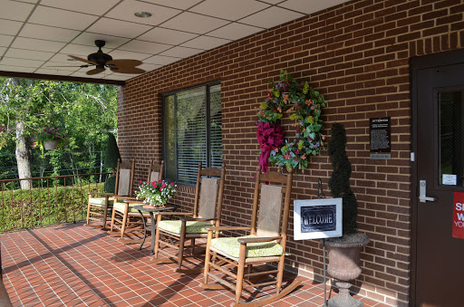 A cozy porch area featuring rocking chairs and a colorful wreath, perfect for relaxing.