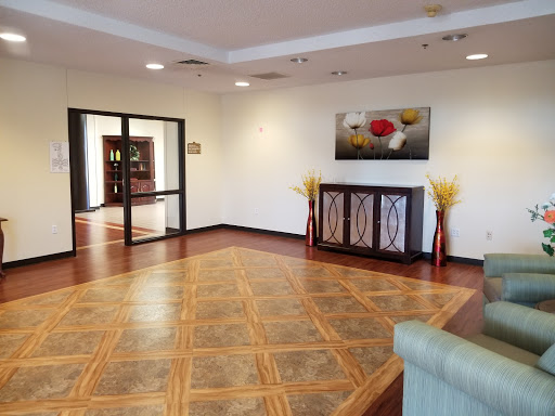 A spacious and elegantly designed lobby featuring wooden flooring, decorative furniture, and modern artwork.