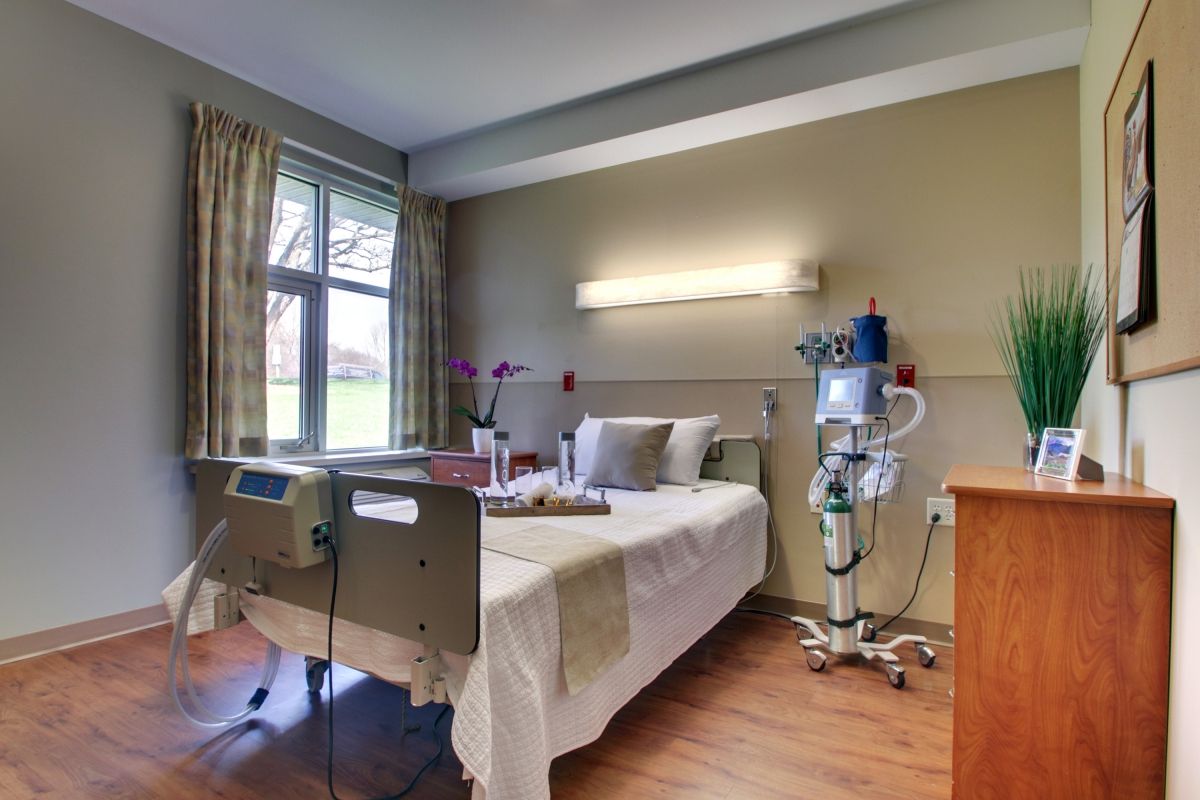 A well-lit hospital room with a bed and medical equipment by the side.