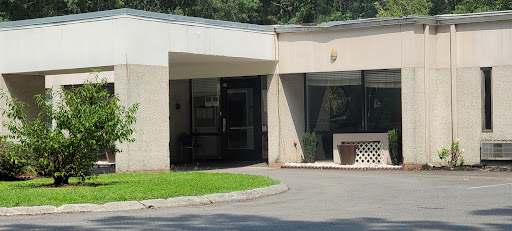 A view of the entrance to a modern building, featuring large glass doors and surrounding greenery.