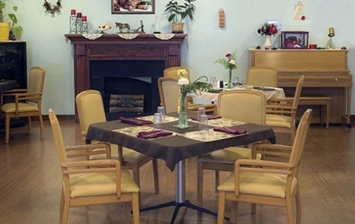 A cozy dining area with a table set for four, featuring a fireplace in the background.