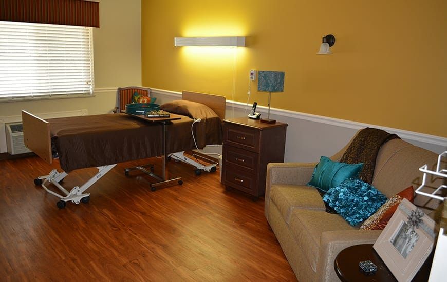 A cozy room featuring a hospital bed, sofa, and warm lighting.