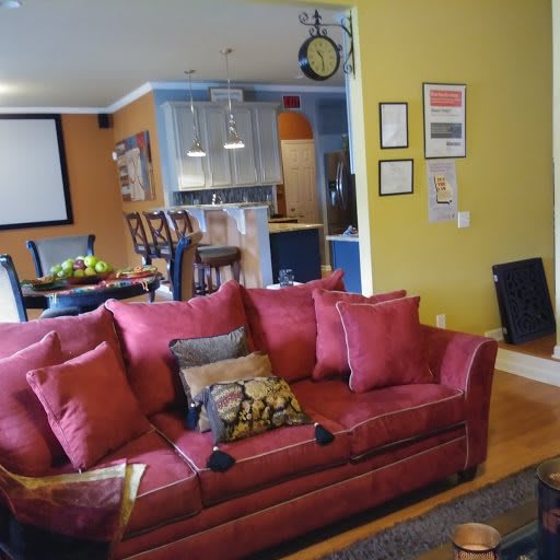 A cozy living room with a vibrant red sofa and an open-plan kitchen in the background, showcasing colorful walls and modern decor.