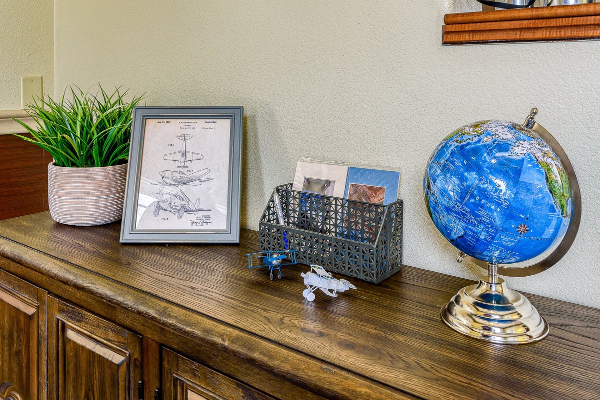 A stylish wooden sideboard featuring a decorative globe, framed artwork, and organized items in a wire basket.