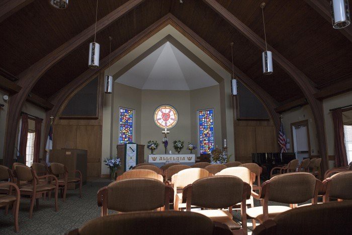A serene church interior featuring wooden pews, a central altar, and colorful stained glass windows.