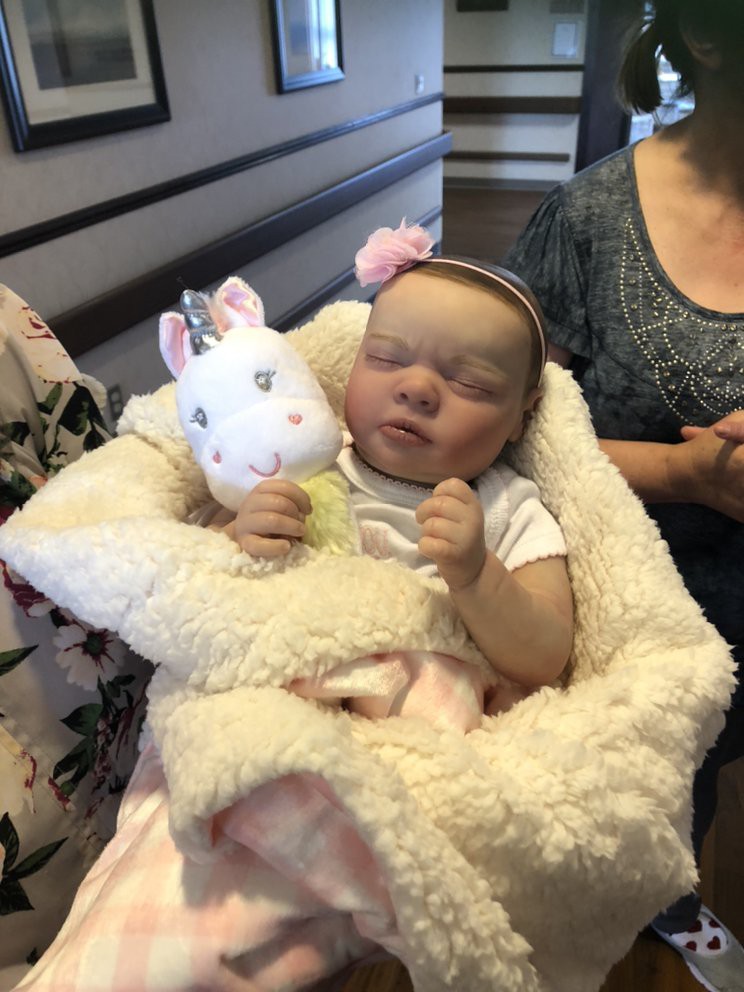 A baby is wrapped in a fluffy blanket, holding a plush unicorn toy.