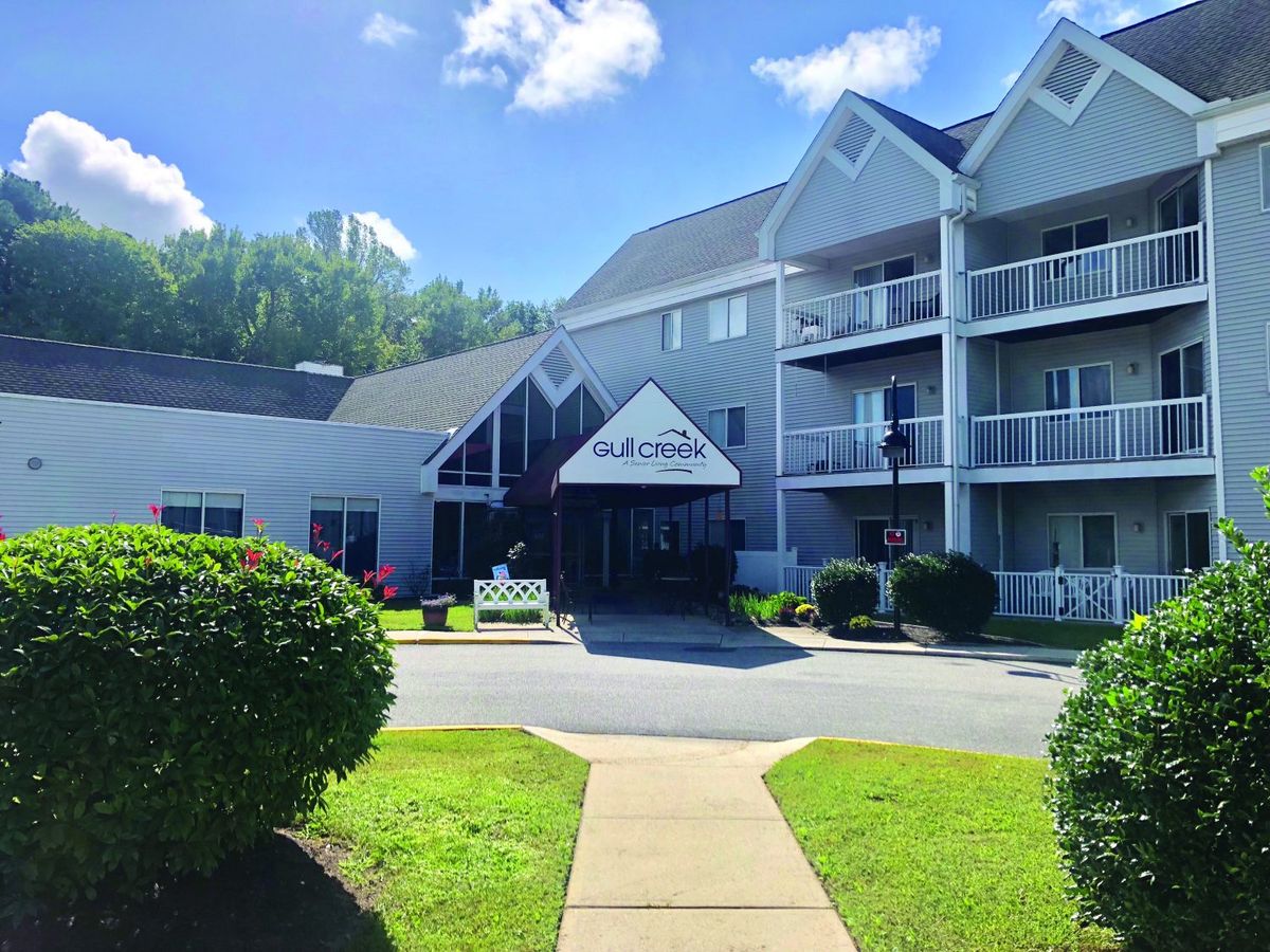 A sunny day view of a multi-story building with balconies and manicured landscaping.